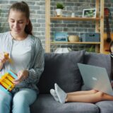 Woman and girl on couch with laptop and toy.