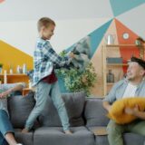 Family having a pillow fight on the couch.