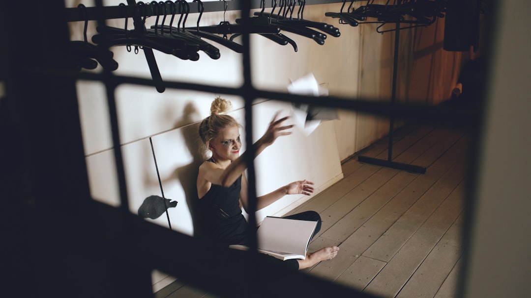 Young woman sitting on floor, throwing papers