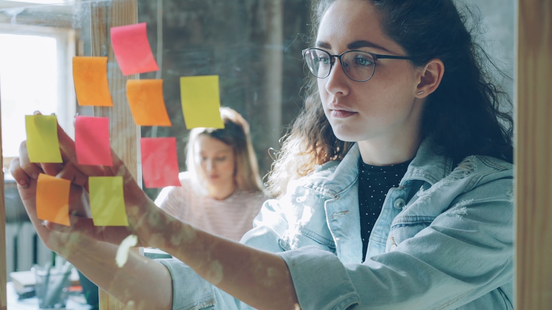 Woman analyzes sticky notes on glass.