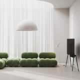 a living room with a green couch and a white lamp