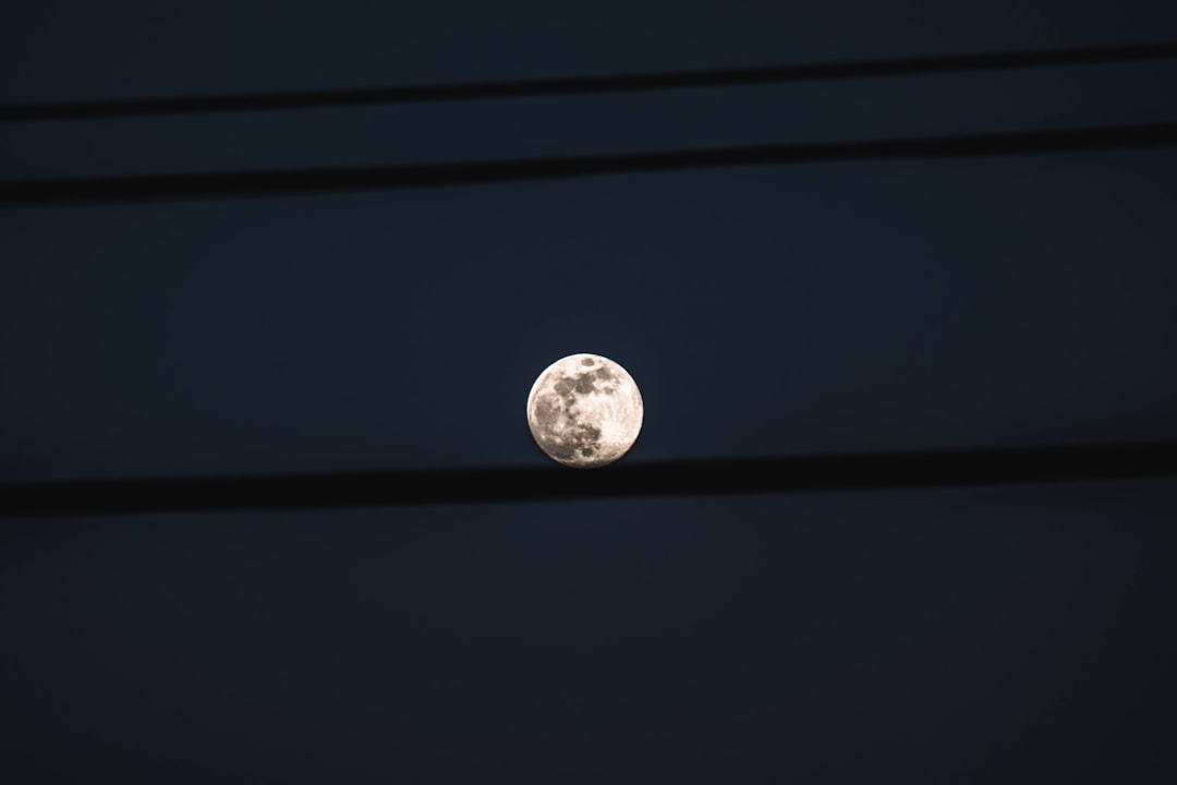 a full moon seen through power lines at night