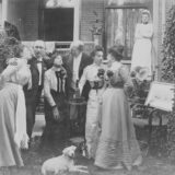 Group of people posing outside a house with a dog.