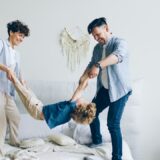 a man and a woman playing with a child on a bed