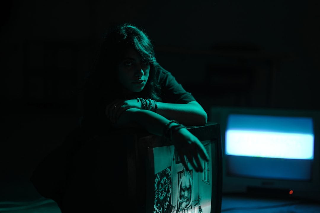 Young woman illuminated by television screen in darkness