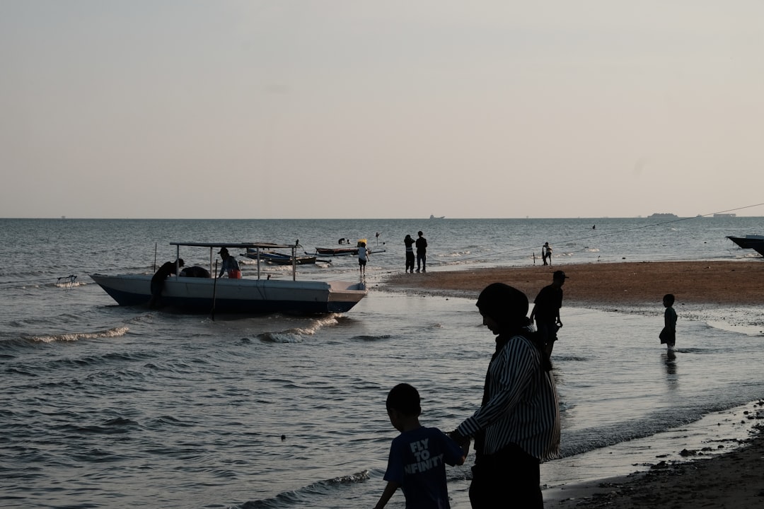 People on a beach with a boat in the water.