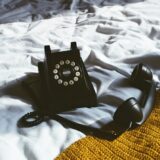 black leather sling bag on white textile