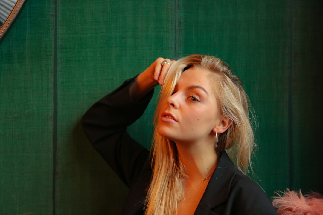 a woman with long blonde hair standing in front of a green wall