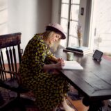 woman in yellow and black floral dress sitting on brown wooden chair