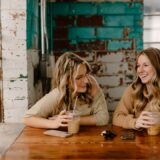 two women sitting at a table with drinks