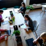 Vrouwen werken samen op laptops aan een houten tafel op een flexplek