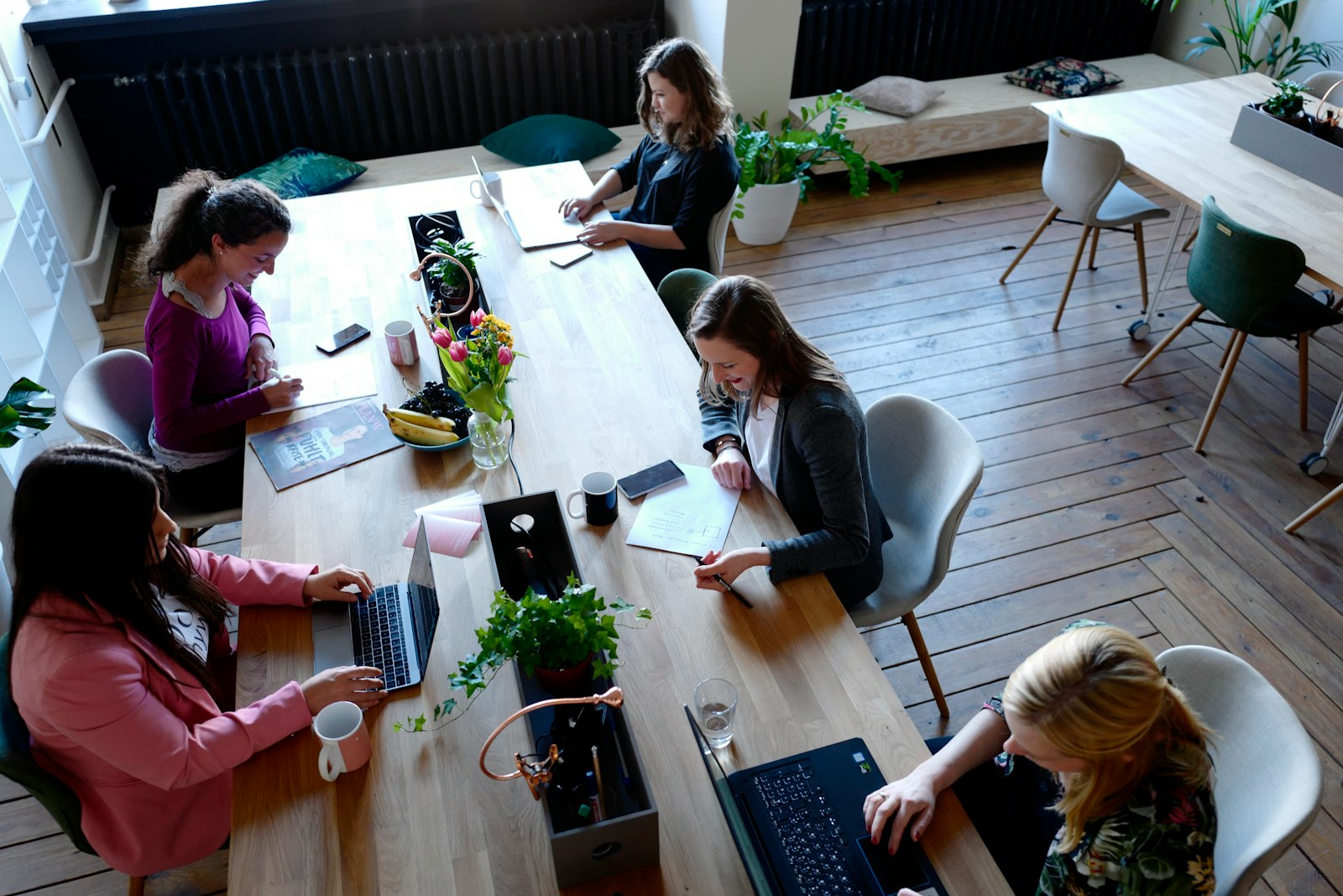 Vrouwen werken samen op laptops aan een houten tafel op een flexplek