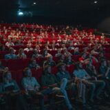 Lege bioscoopzaal met rode stoelen en een verlicht doek