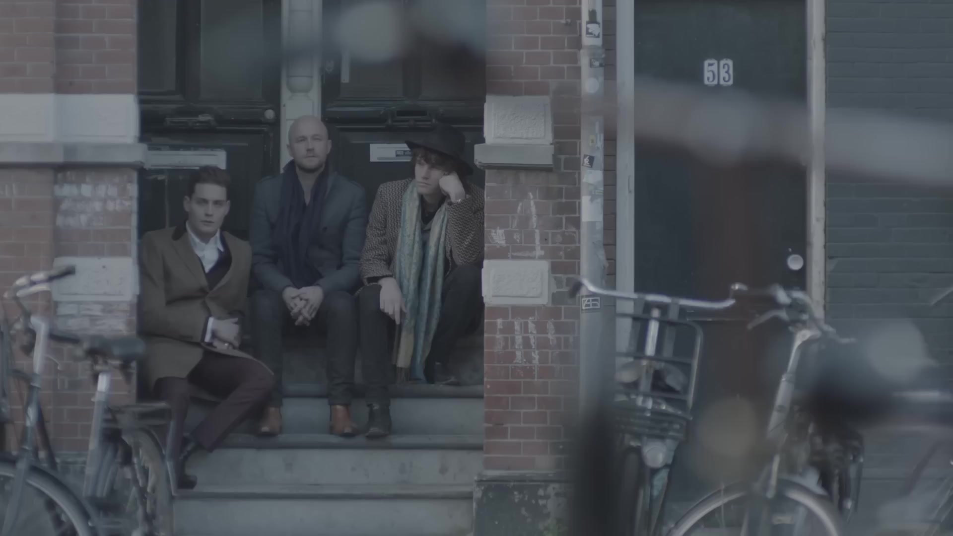 Douwe Bob met hoed op een stoep in Amsterdam in de videoclip van Slow Down
