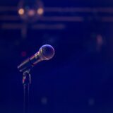 Microfoon op een lege studiovloer onder felle podiumlampen