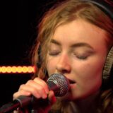 Zangeres Froukje zingt met een koptelefoon op achter de microfoon in een radiostudio