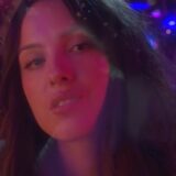 Olivia Rodrigo in paars en roze licht in de videoclip van drop dead