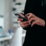 Handen houden een telefoon vast waarop door een tijdlijn met advertenties wordt gescrold