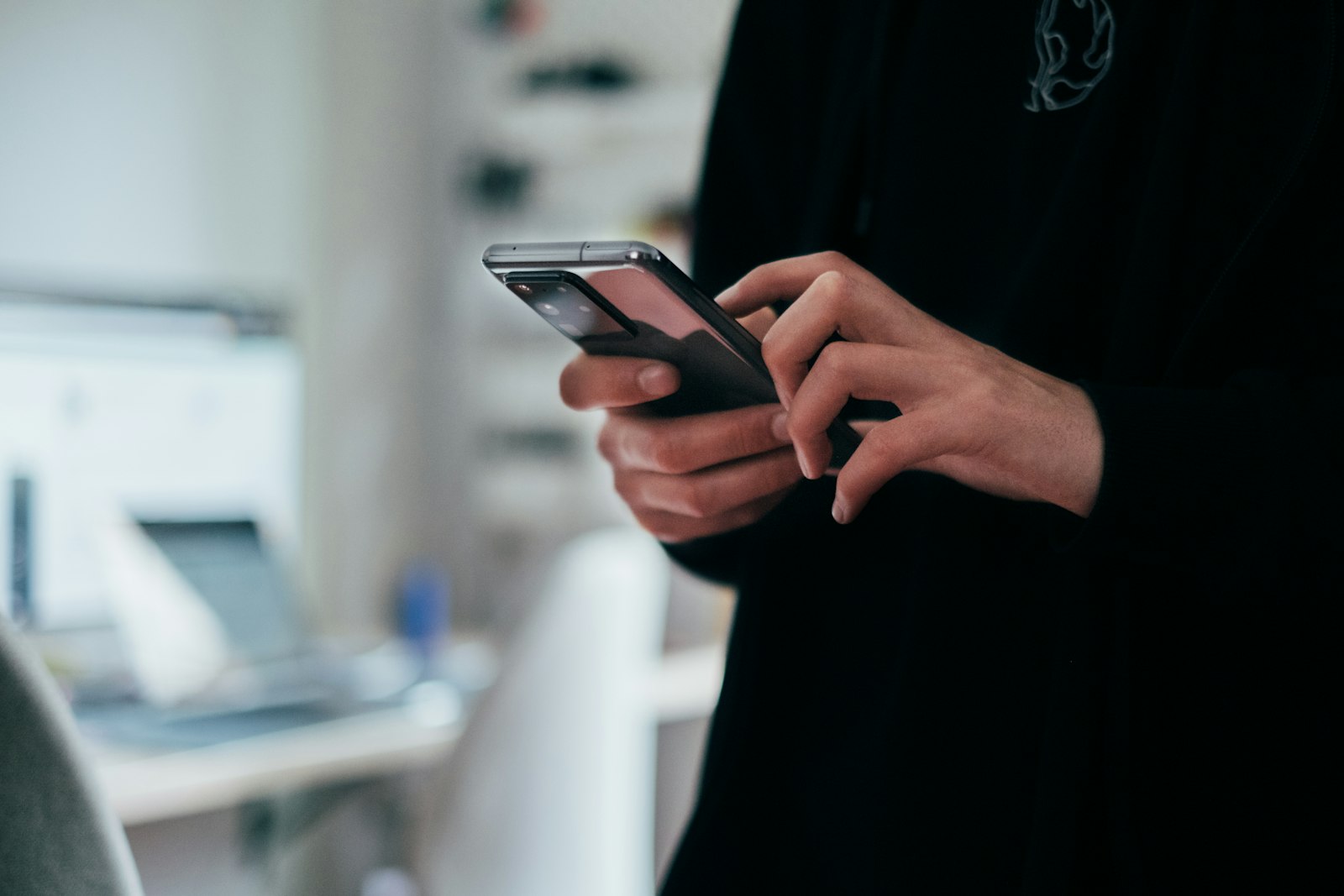 Handen houden een telefoon vast waarop door een tijdlijn met advertenties wordt gescrold