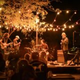 Feestelijk gedekte tafels en een klein podium voor een band op een bruiloft in de buitenlucht