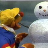 Ernie uit Sesamstraat bij een sneeuwpop in een oude aflevering van de Nederlandse serie