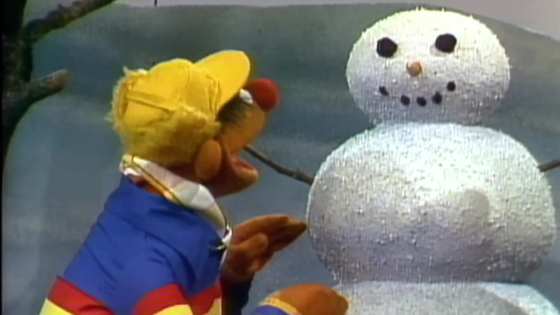 Ernie uit Sesamstraat bij een sneeuwpop in een oude aflevering van de Nederlandse serie