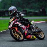 Motorcoureur hangt in een bocht op een nat circuit