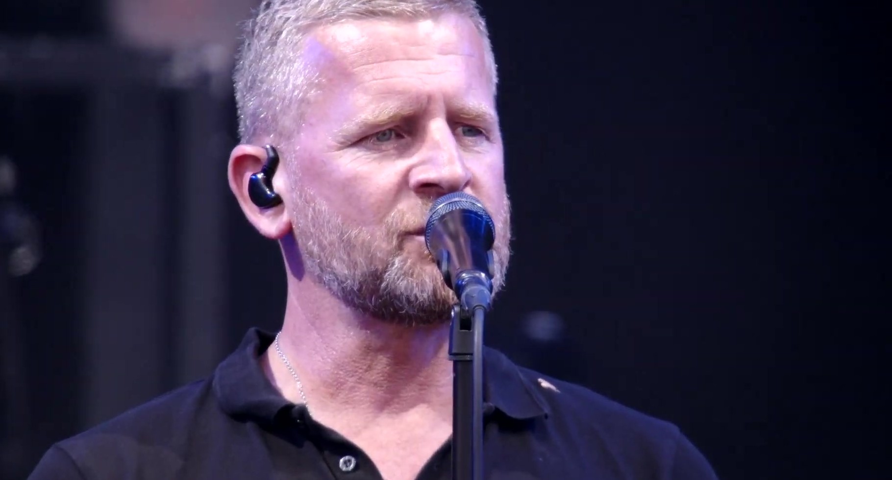 De zanger van Racoon zingt live op een podium met een oortje in