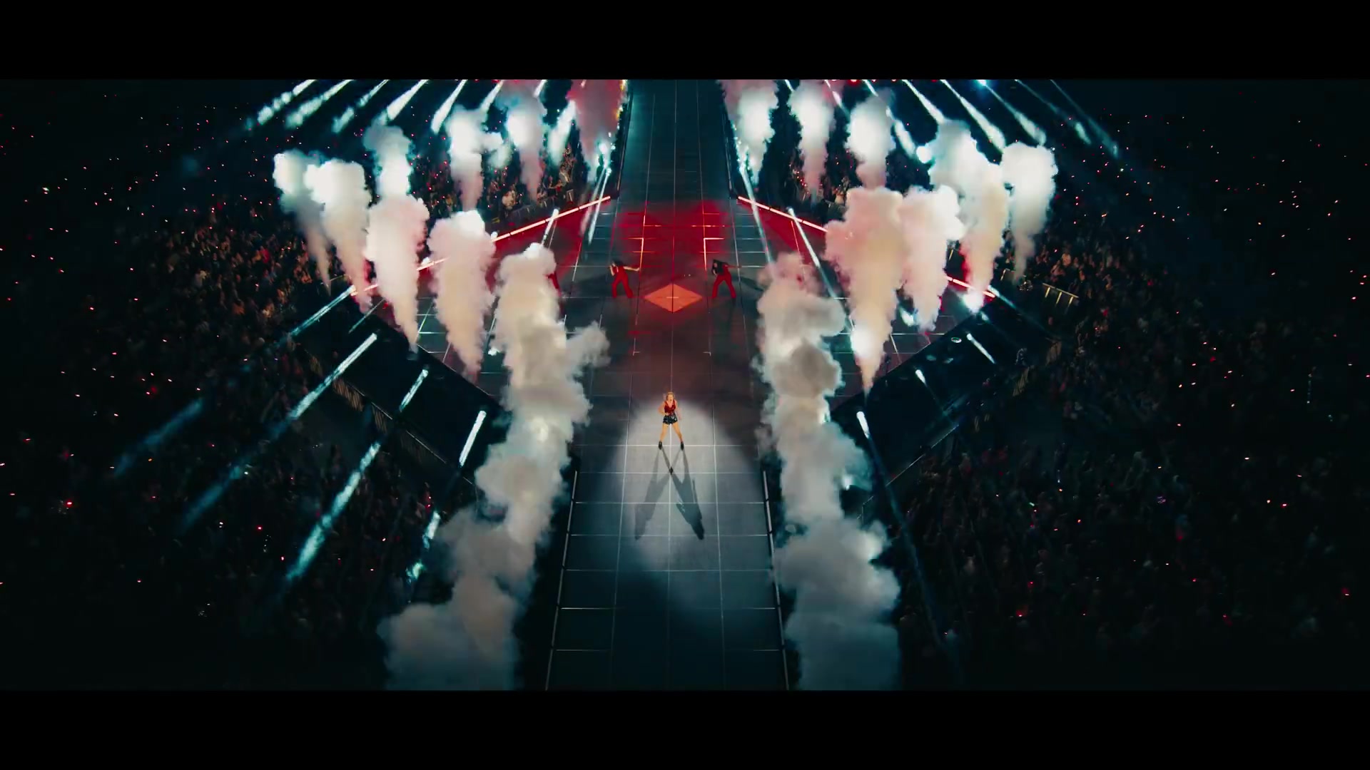 Taylor Swift op het podium tijdens The Eras Tour met rookzuilen aan weerszijden