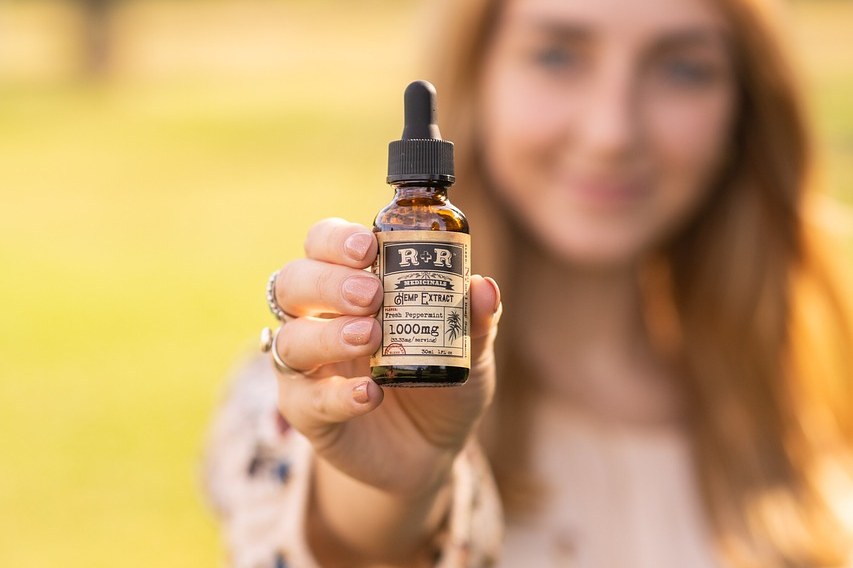 Vrouw houdt een flesje CBD-olie vast