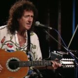 Brian May speelt op een akoestische twaalfsnarige gitaar
