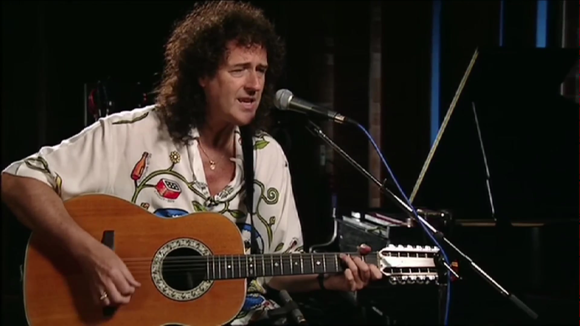 Brian May speelt op een akoestische twaalfsnarige gitaar