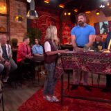 Carrie ten Napel in de studio van Carrie op vrijdag met gasten en publiek rond een tafel met een tapijtkleed