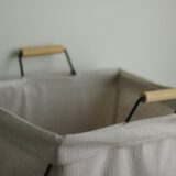 Wasmand van stof en hout tegen een lichte muur
