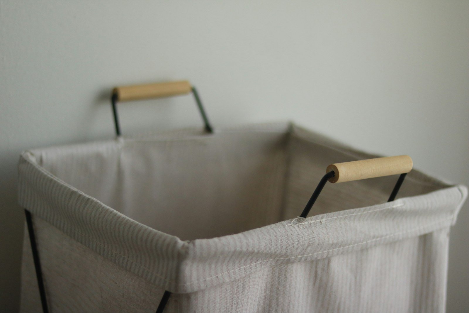 Wasmand van stof en hout tegen een lichte muur