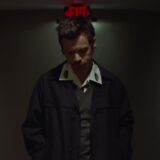 Harry Styles onder een rood exitbord in de officiële videoclip van Aperture