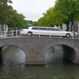 De witte limousine van Het Familiediner op een brug over een gracht