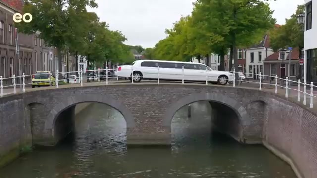De witte limousine van Het Familiediner op een brug over een gracht