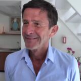 Cornald Maas in een lichtblauw overhemd lacht tijdens een interview