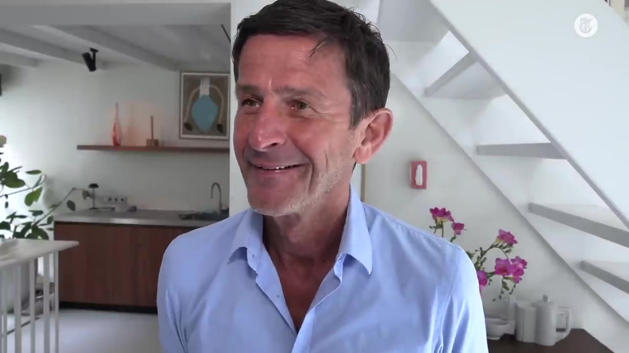 Cornald Maas in een lichtblauw overhemd lacht tijdens een interview