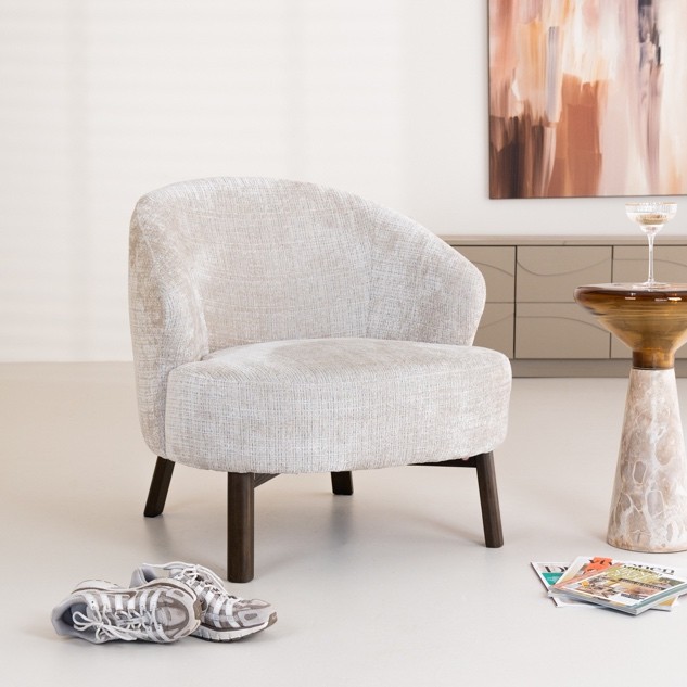 Lichte fauteuil naast een travertin bijzettafel