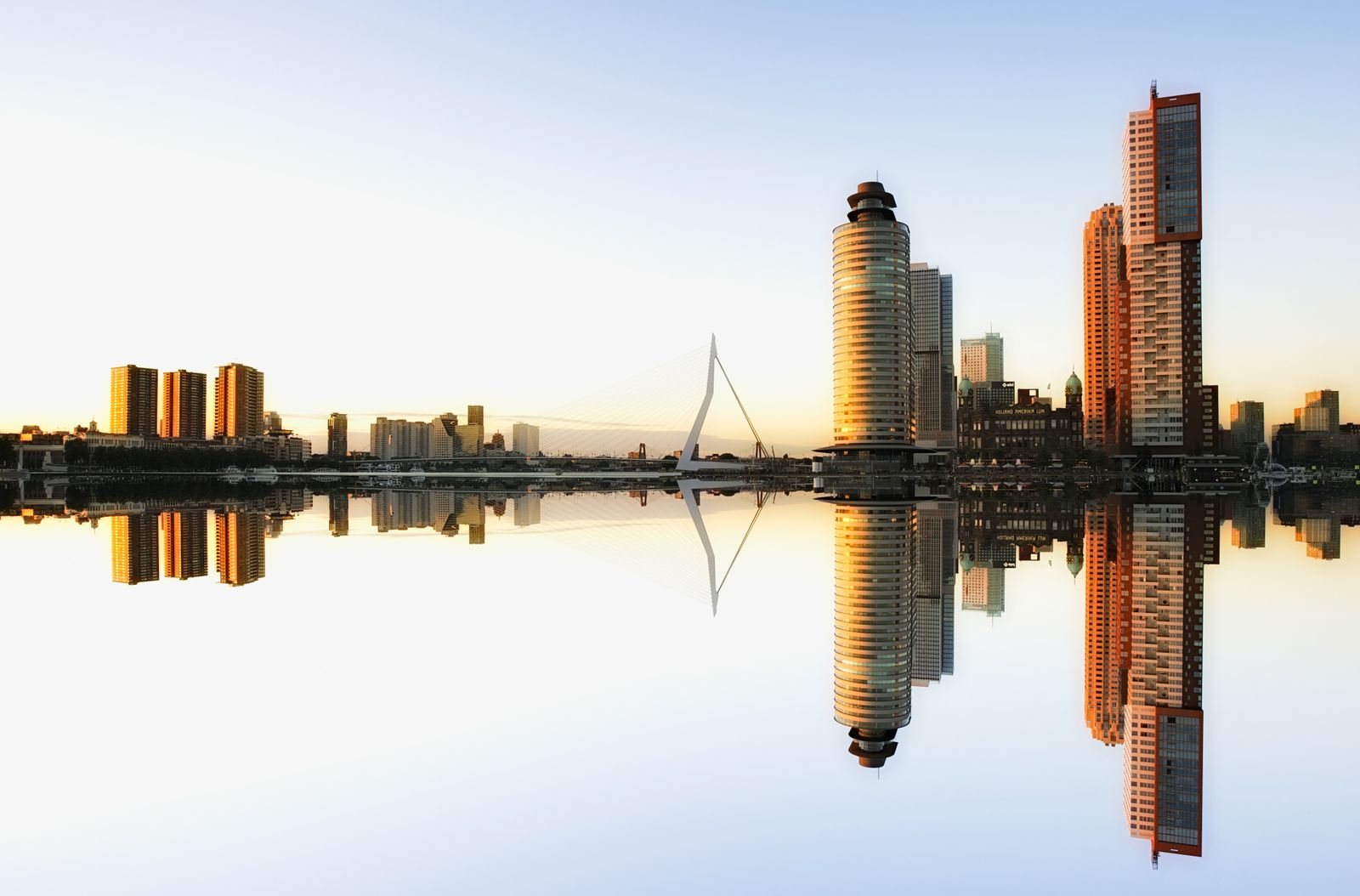 Skyline van Rotterdam weerspiegeld in de Maas bij zonsopkomst