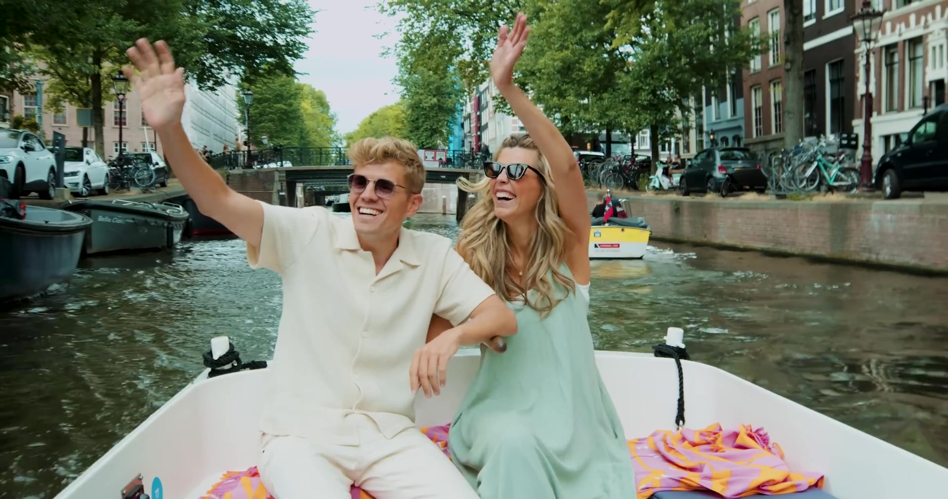 Jaap Reesema zwaait lachend vanuit een bootje op een Amsterdamse gracht