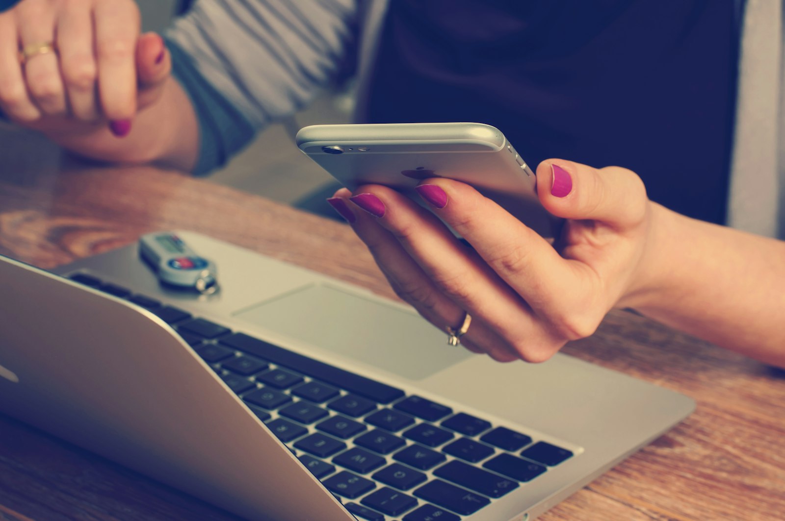 Smartphone met een verdacht bericht op een tafel naast een laptop