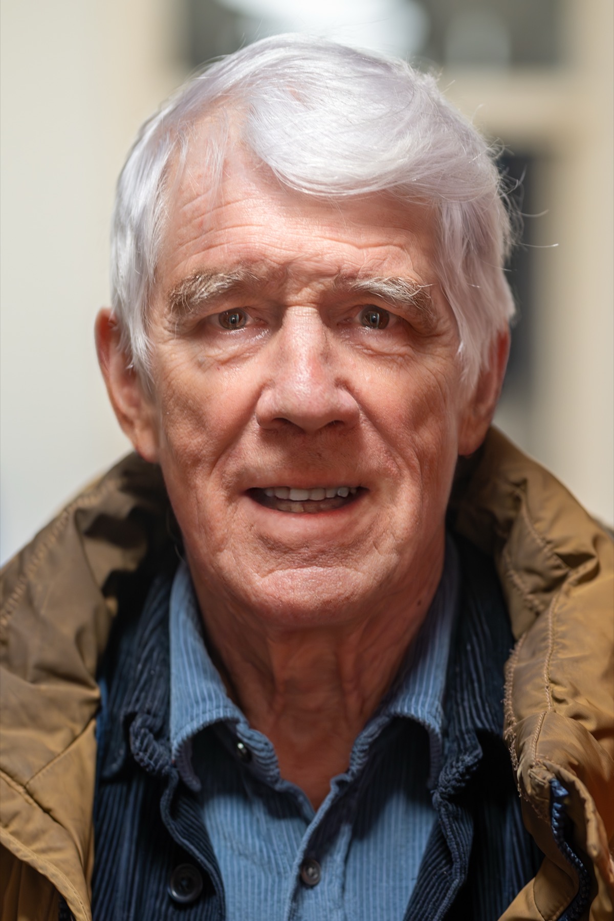 Portret van Kees van Kooten met wit haar en een bruine jas in 2023