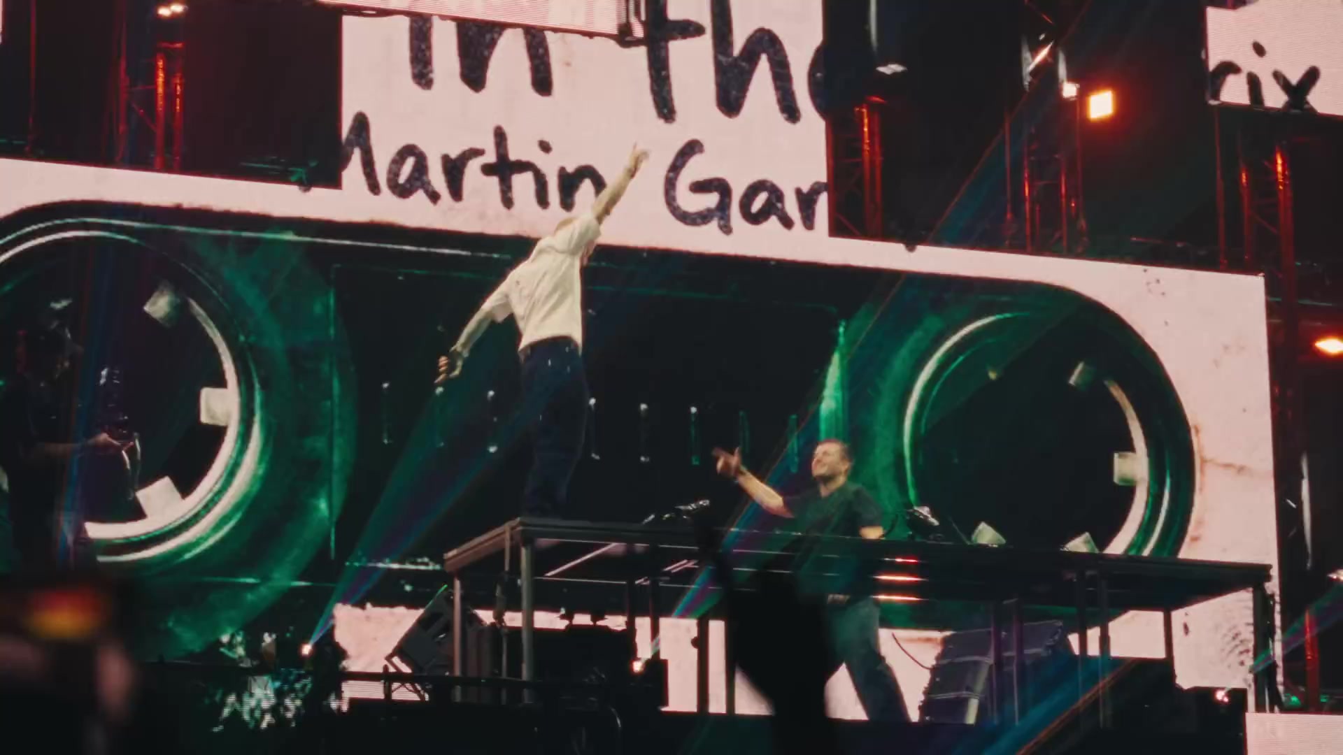 Martin Garrix springt op het podium voor een groot scherm met zijn naam