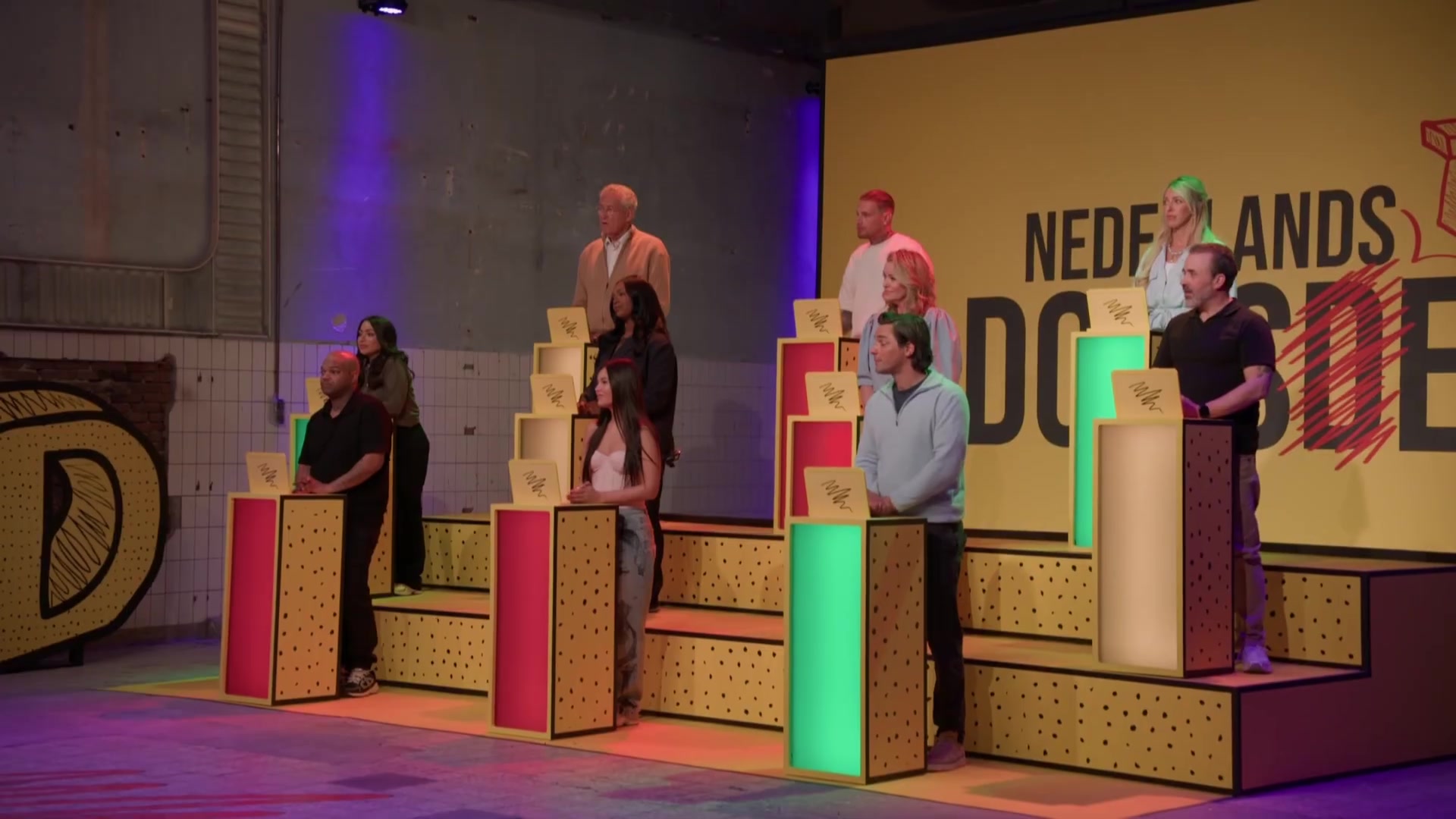 De tien kandidaten van Nederlands Domste achter hun gele zuiltjes in de studio