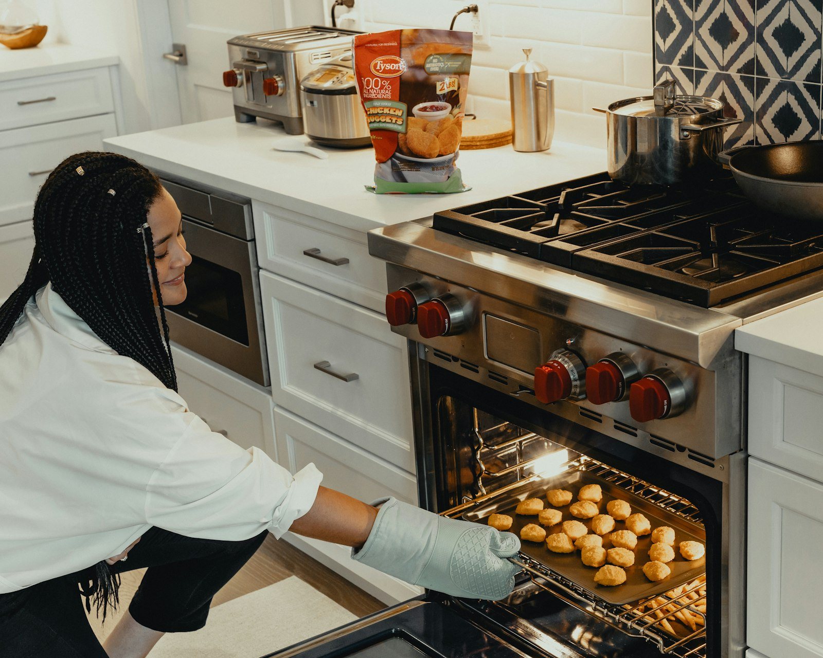 Vrouw haalt een bakplaat uit de oven in een lichte keuken