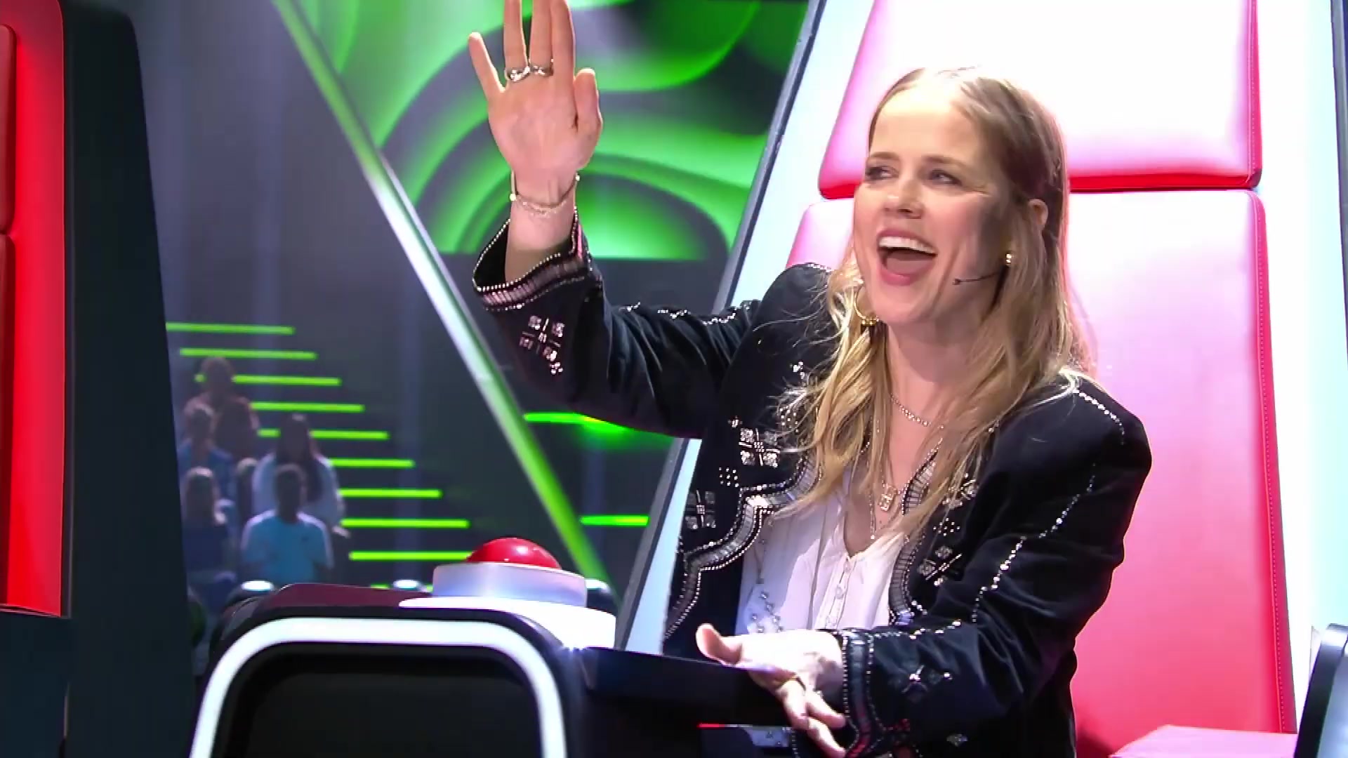 Ilse DeLange zwaait lachend vanuit haar rode draaistoel bij The Voice