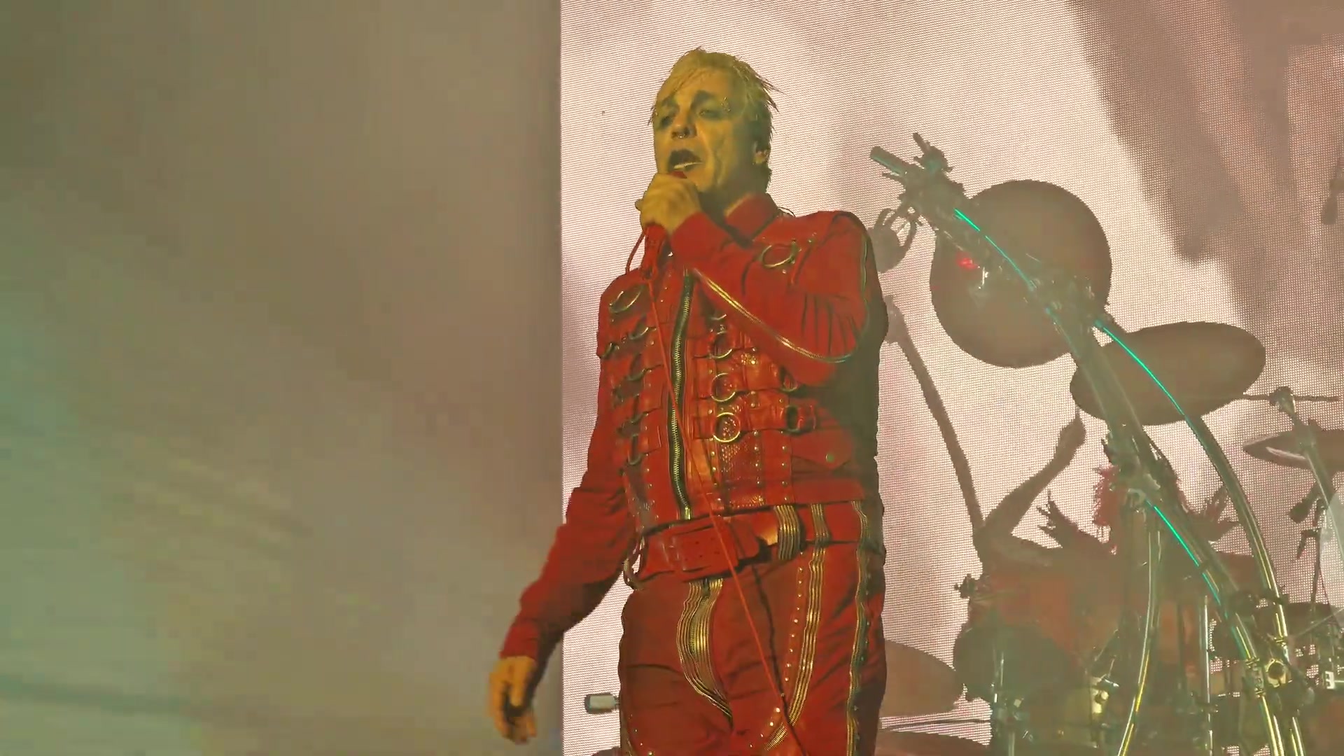 Till Lindemann in een rood pak op het podium tijdens zijn solotour